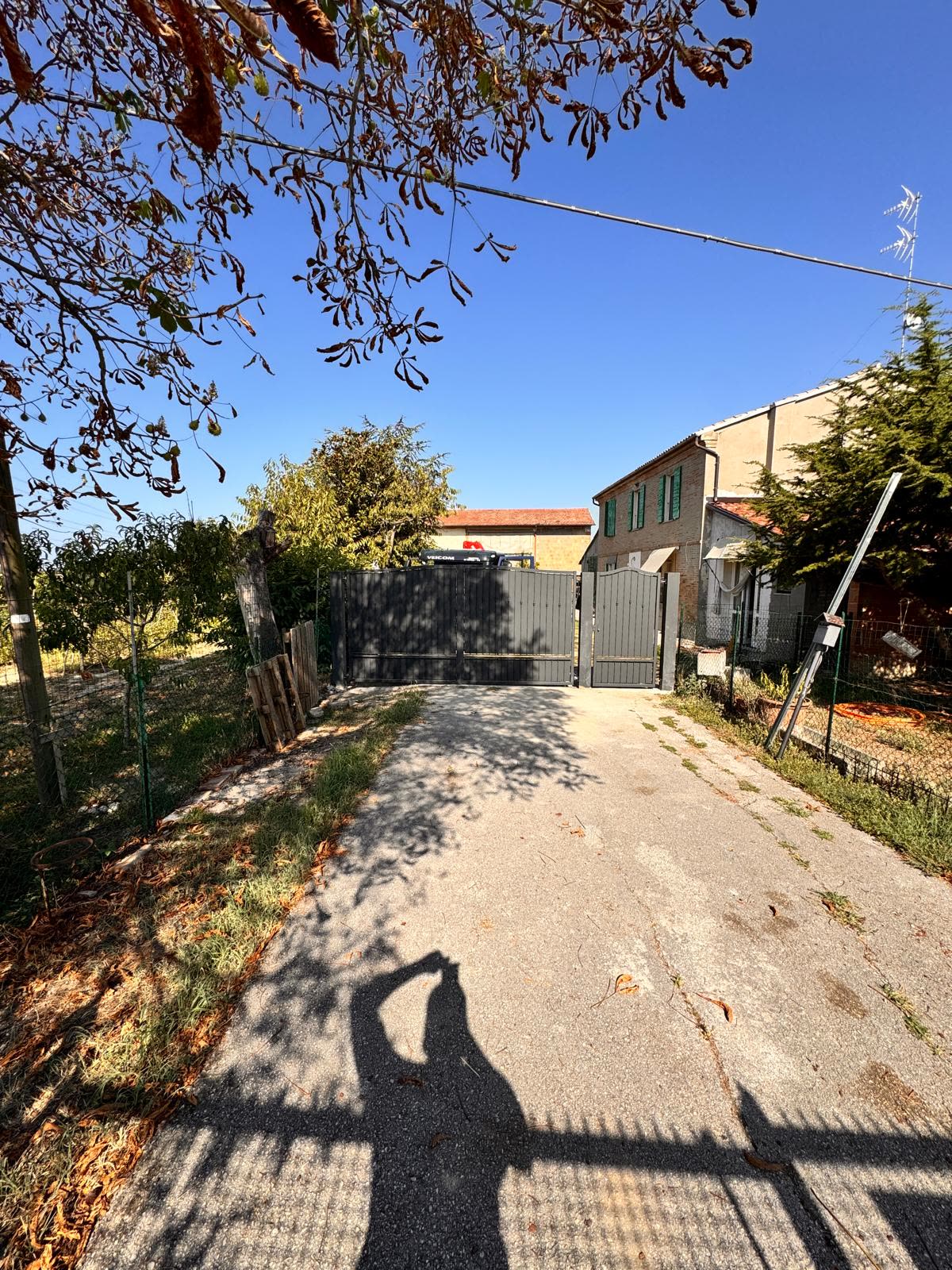 Il vialetto d'accesso con il cancello carraio a doghe verticali in fondo